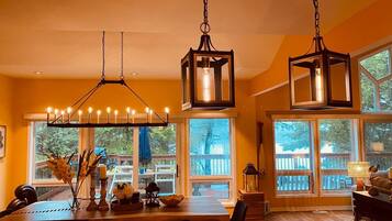 A dining area with a chandelier, large windows, and a view of the outdoors.