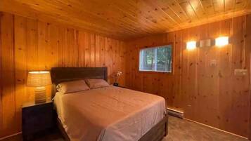 A wooden-paneled bedroom with a bed, nightstands, and wall-mounted lights.