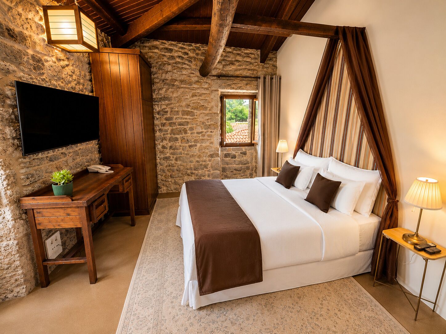 A bedroom with a stone wall, wooden furniture, a flat-screen TV, a bed with white and brown bedding, and a window with curtains.