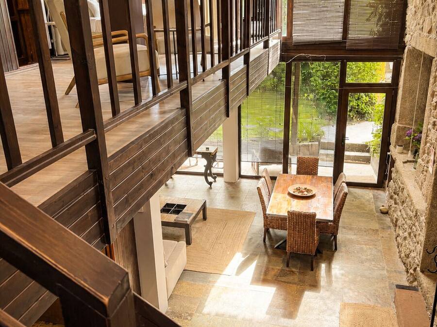 Un intérieur spacieux avec un plafond haut, un coin repas comprenant une table et des chaises, et une vue sur l’extérieur grâce à de grandes fenêtres.