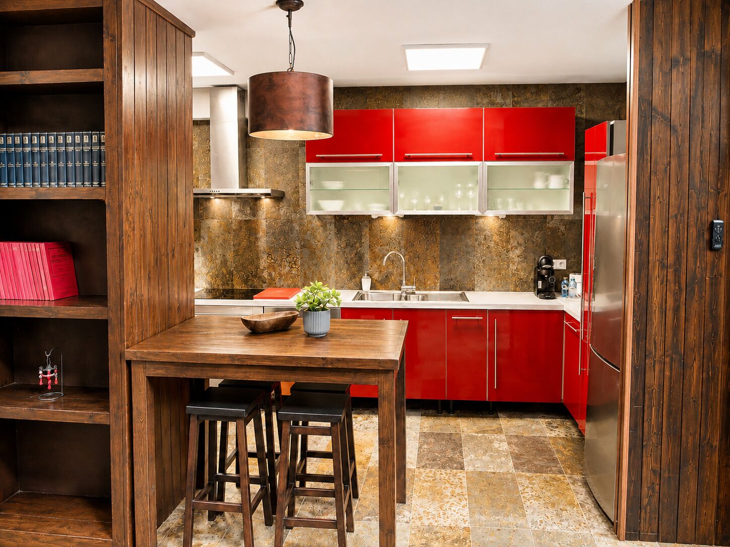 Una cocina moderna con armarios rojos, una mesa de comedor de madera y una lámpara colgante.