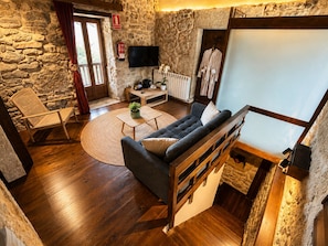 A cozy living room with a stone wall, a sofa, a wooden coffee table, a chair, and a television.