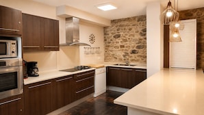A modern kitchen with dark wood cabinets, stainless steel appliances, a stone accent wall, and pendant lighting.