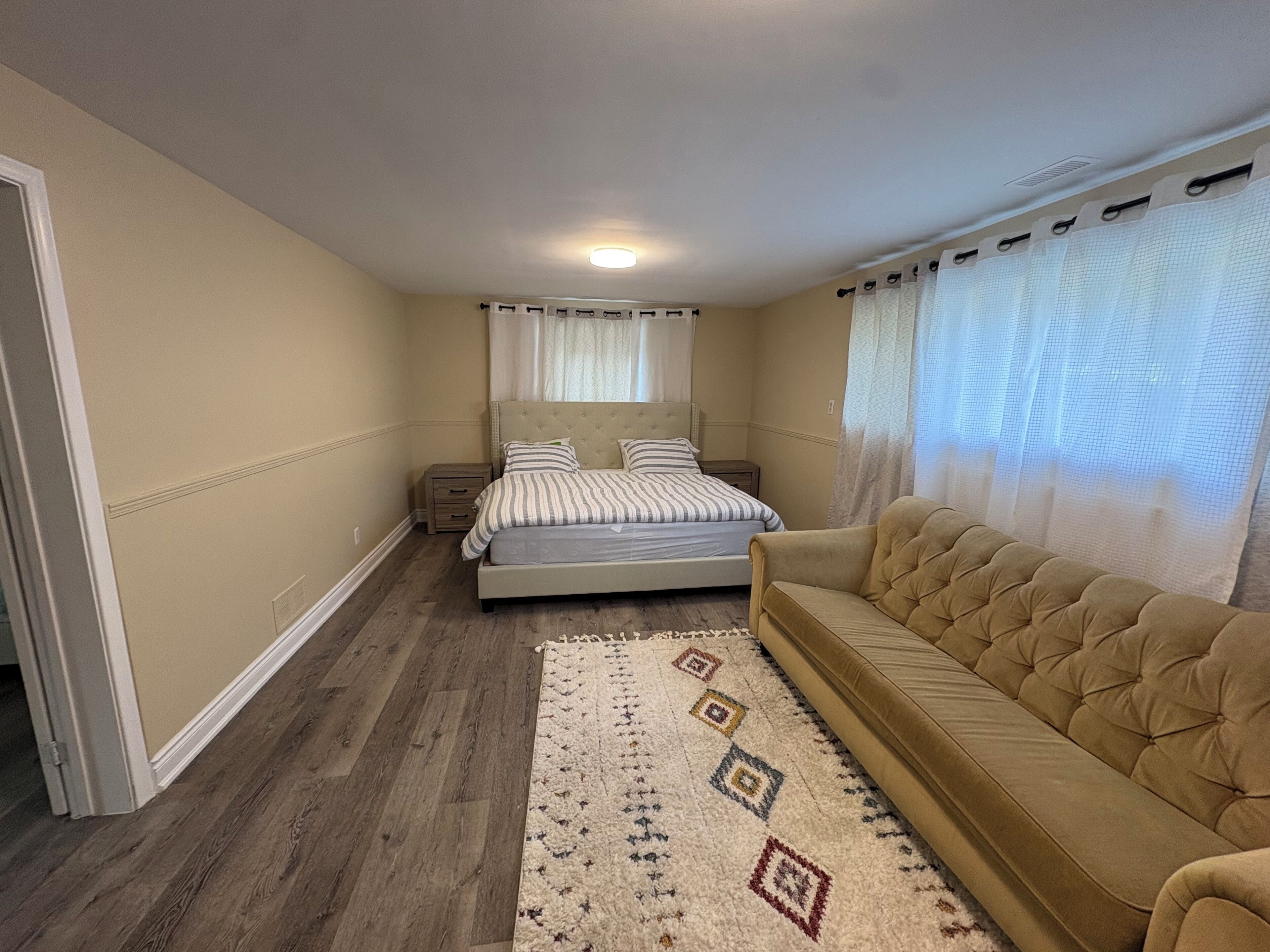 Une chambre à coucher comprenant un lit, un canapé, une table de chevet et un tapis à motifs.