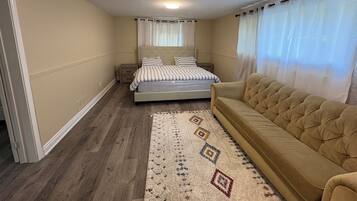 Une chambre à coucher comprenant un lit, un canapé, une table de chevet et un tapis à motifs.