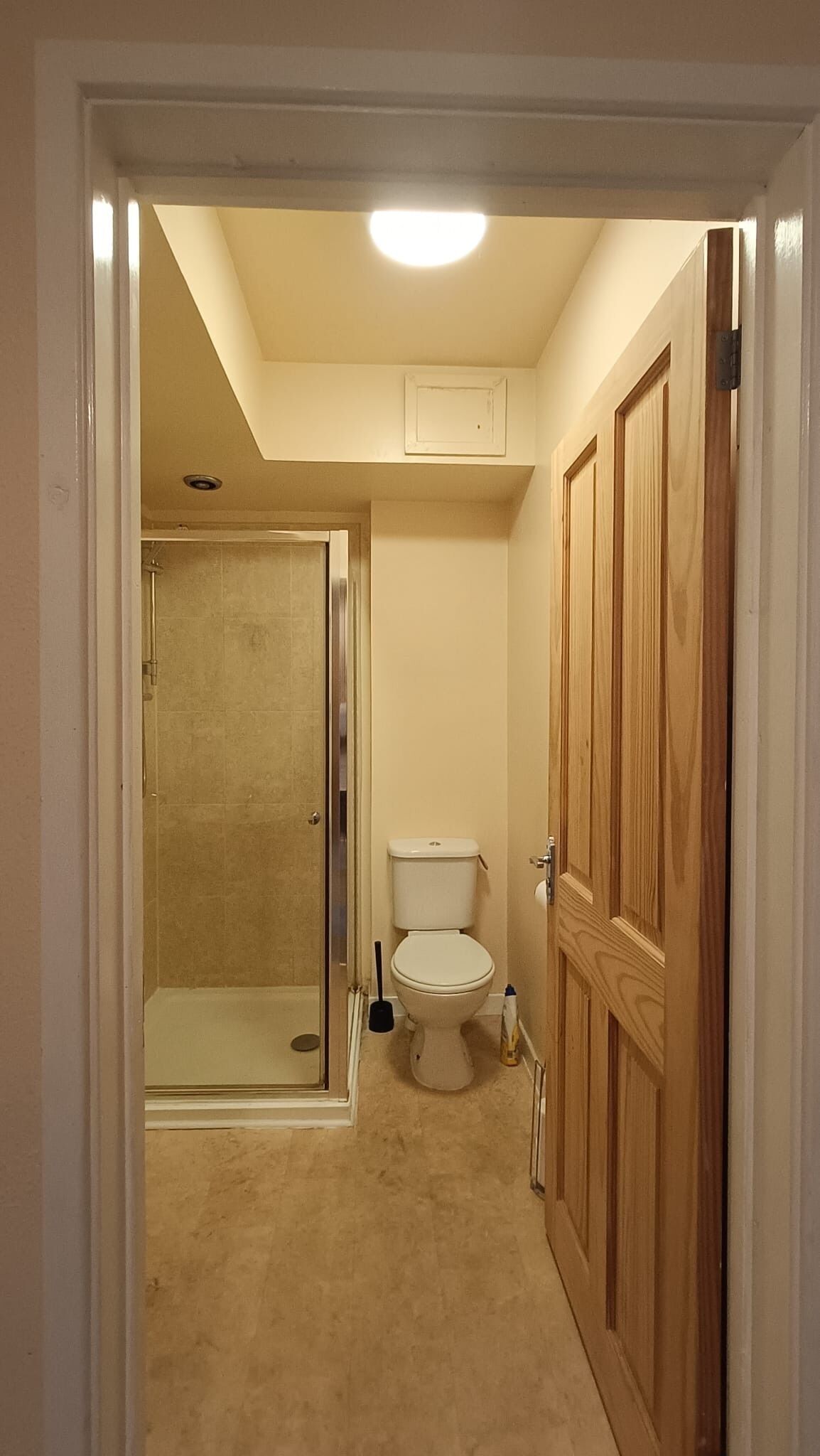 A bathroom with a toilet, shower, and wooden doors.