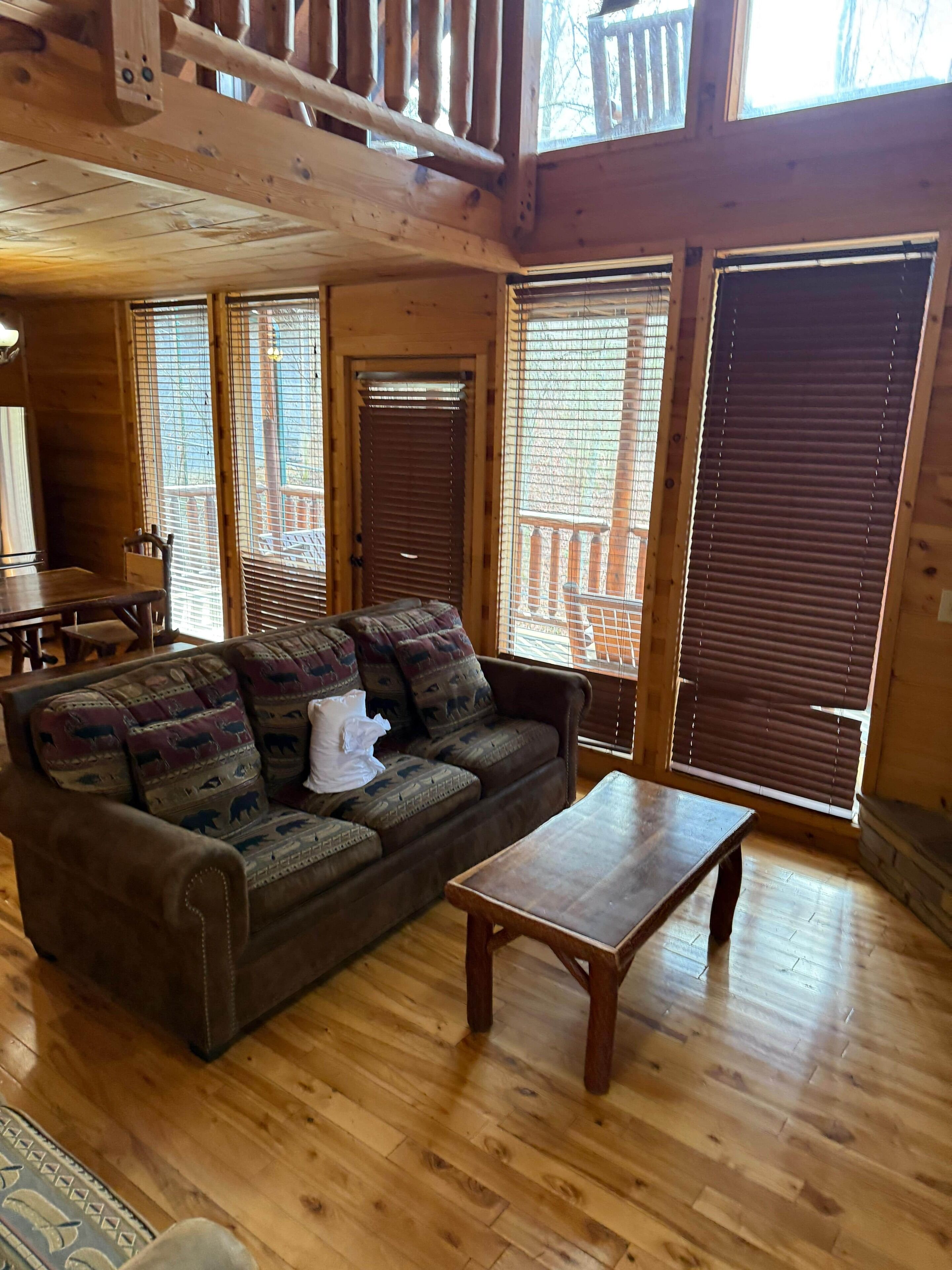 Un interior de madera con un sofá, una mesita y una ventana con persianas.
