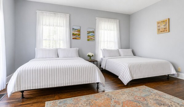 A bedroom with two beds, a rug, and artwork on the wall.