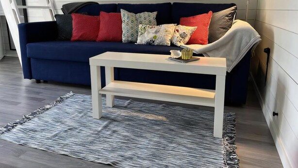 Ein Zimmer mit einem dunkelblauen Sofa, einem weißen Couchtisch und einem gemusterten Teppich.