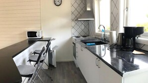 Eine kleine Küche mit Mikrowelle, Herd, Spüle und einem Stuhl.