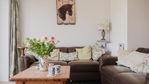 A cozy living room with a brown leather sofa, a wooden coffee table with decorative items, and a wall-mounted sign with a horse illustration. - Kempsey House -  Frampton on Severn, Gloucester, Tewkesbury (Frampton on Severn)