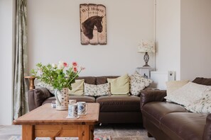 A cozy living room with a brown leather sofa, a wooden coffee table with decorative items, and a wall-mounted sign with a horse illustration. - Kempsey House -  Frampton on Severn, Gloucester, Tewkesbury (Frampton on Severn)