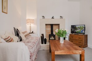 Een woonkamer met een bank, een houten salontafel, een open haard en een televisie.