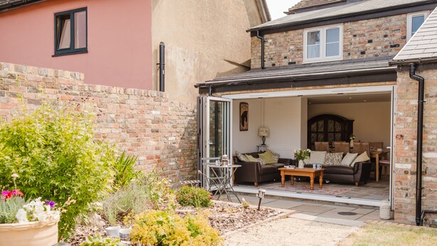 An open patio with a seating area, a brick wall, and a garden with various plants. - Kempsey House -  Frampton on Severn, Gloucester, Tewkesbury (Frampton on Severn)