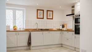 A modern kitchen with white cabinets, a stainless steel range hood, and a window with decorative curtains. - Kempsey House -  Frampton on Severn, Gloucester, Tewkesbury (Frampton on Severn)