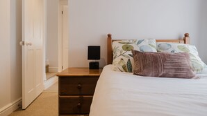 A bedroom with a bed, a nightstand, a lamp, and a door leading to another room. - Kempsey House -  Frampton on Severn, Gloucester, Tewkesbury (Frampton on Severn)