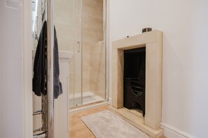 Een badkamer met een douchecabine van glas, een wit wastafelmeubel en een handdoekrek.