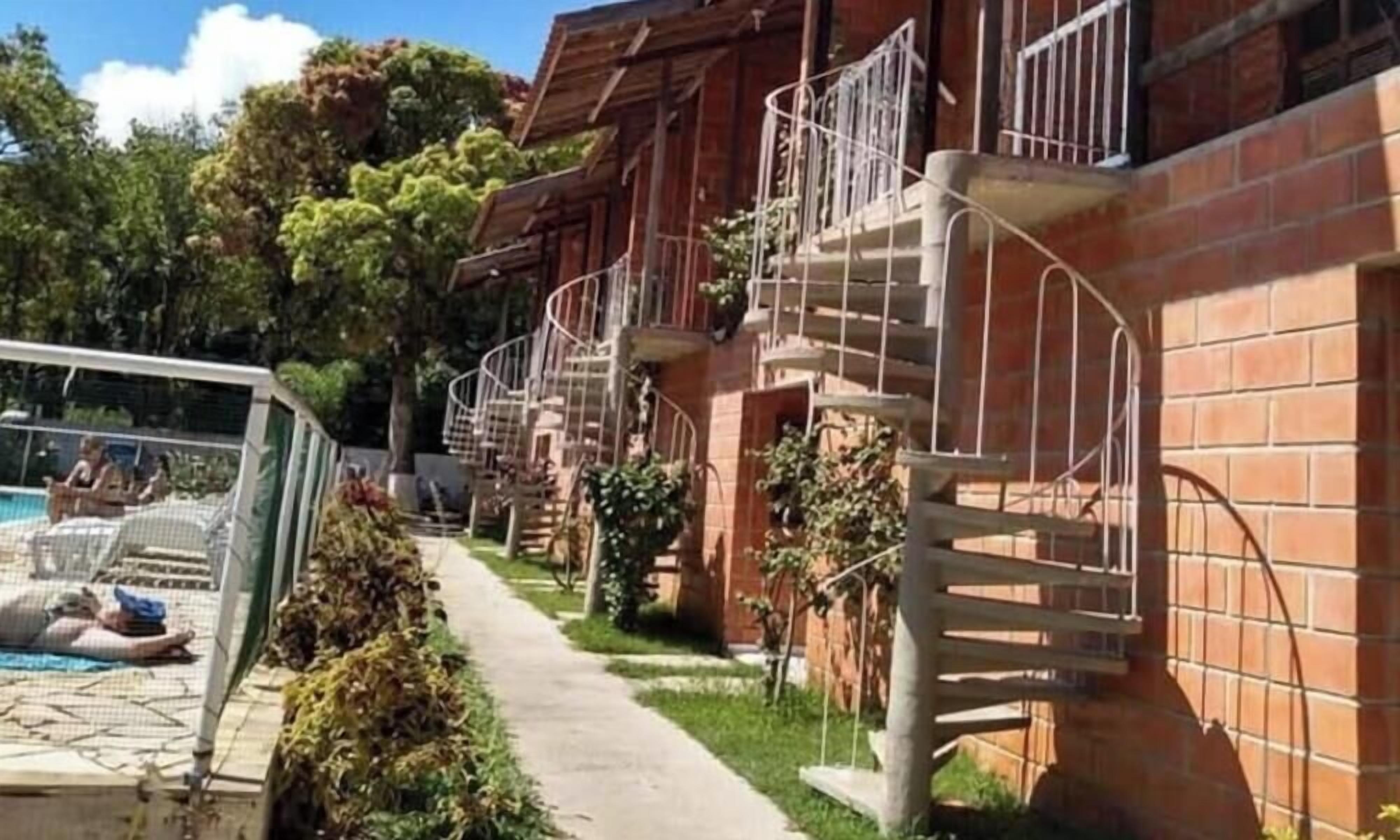 A row of brick buildings with balconies, a pool area, and a pathway.