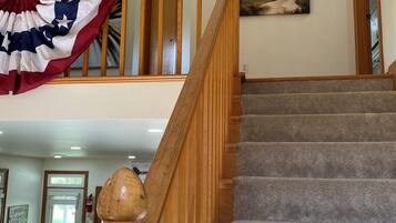 A staircase with a wooden handrail and carpeted steps leading to an upper level.