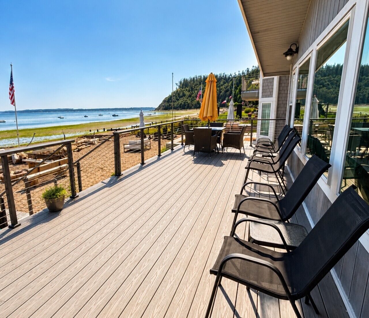 A wooden deck with outdoor seating, a view of the beach, and a flag.