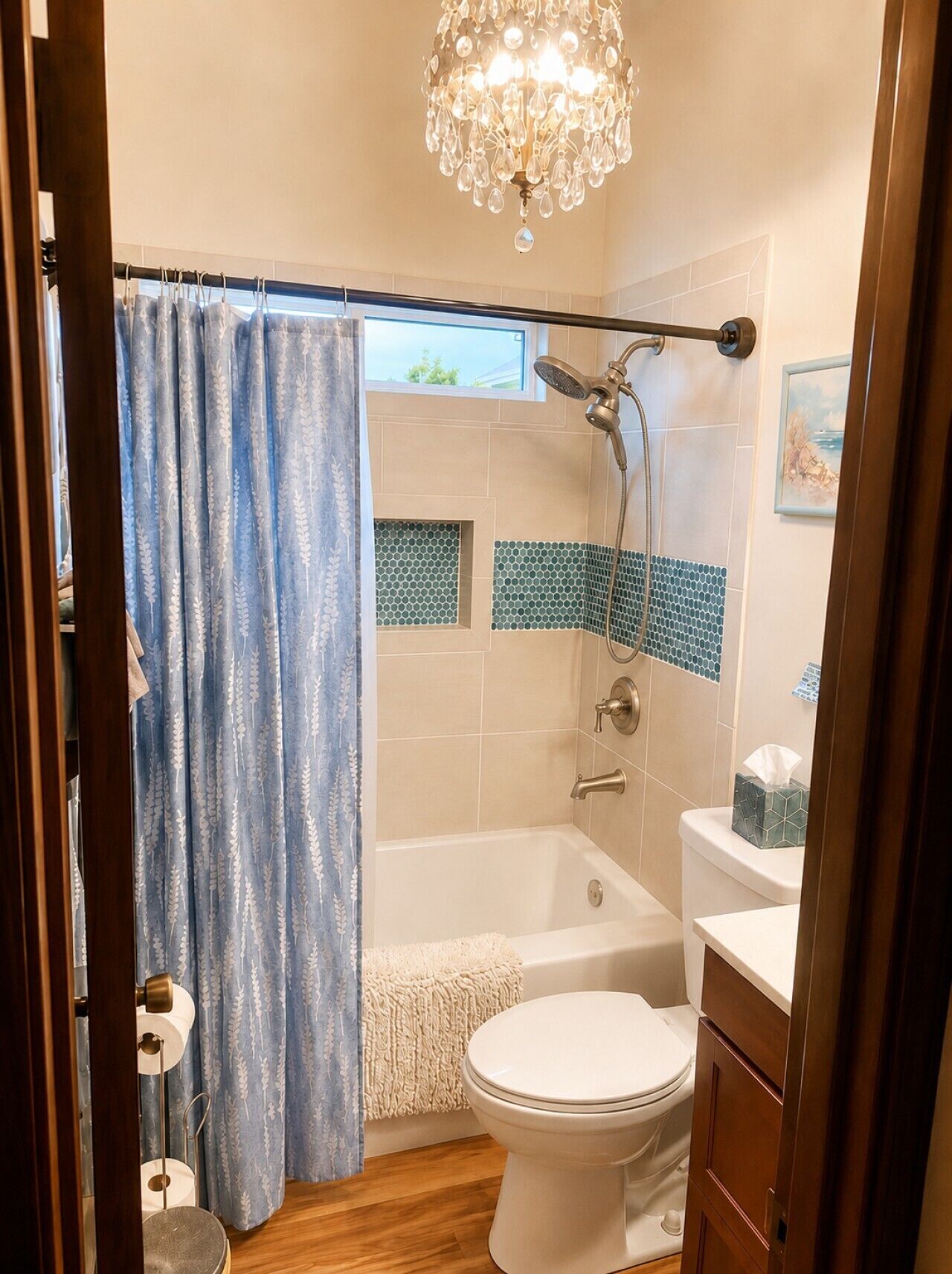 A bathroom with a bathtub, toilet, shower, and a chandelier.