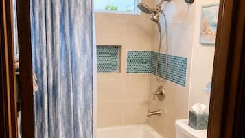 A bathroom with a bathtub, toilet, shower, and a chandelier.