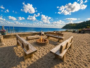 Uma praia com bancos de madeira e um canteiro de fogueira central.