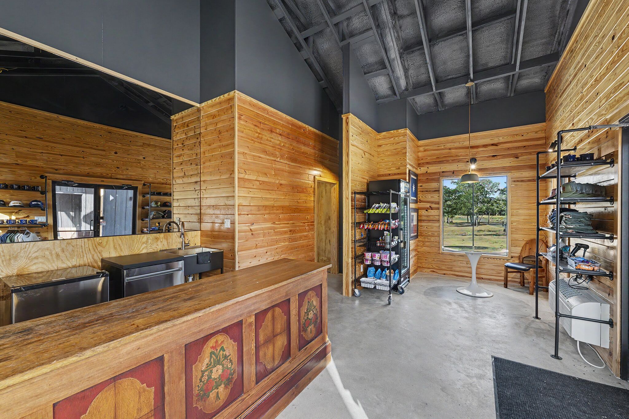 A wooden interior with a reception desk, a shoe display, and a view of the outdoors.