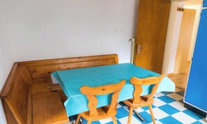 A small dining area with a wooden bench and two wooden chairs, a blue tablecloth, and a checkered floor. - SPECTACULAR VIEWS OF THE MATTERHORN, THIS WELCOMING ZERMATT APARTMENT (Zermatt)