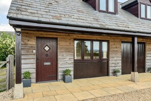 A two-story house with a stone facade, a dark brown front door, and a small garden area with potted plants. - The Donkey Shed -  Sherborne, Dorchester, sleeps 6 guests  in 3 bedrooms (Sherborne)