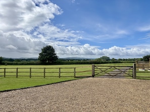 A gravel path leading to a wooden gate in a rural landscape with a large tree and rolling hills in the background. - The Donkey Shed -  Sherborne, Dorchester, sleeps 6 guests  in 3 bedrooms (Sherborne)