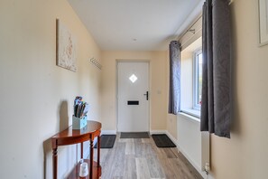 A hallway with a wooden table, a coat rack, a door with a window, and a radiator. - The Donkey Shed -  Sherborne, Dorchester, sleeps 6 guests  in 3 bedrooms (Sherborne)