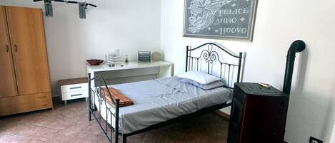 A bedroom with a bed, a wardrobe, a desk, and a radiator.