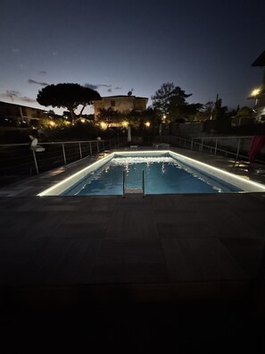 Ein rechteckiger Pool mit Metallgeländer, umgeben von einer gefliesten Terrasse.