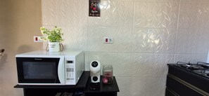 A kitchen with a microwave, a coffee maker, and a small potted plant on a counter. - Chalet at Sítio Bela Vista - 5 Minutes from the City Center (São Bento do Sapucaí)