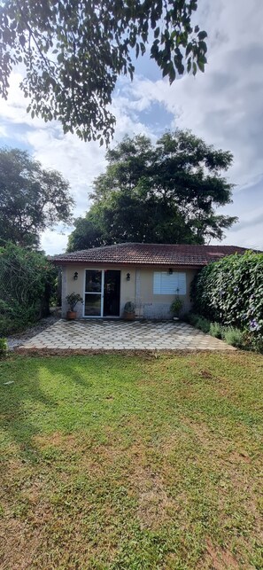 Uma pequena casa com telhado de telhas, porta frontal e um pequeno alpendre.