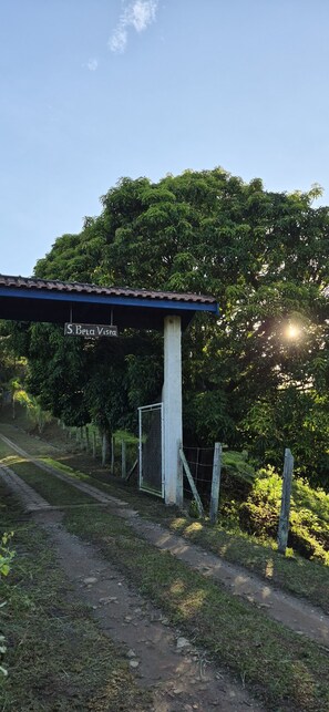 A covered outdoor area with a sign reading 'J. Bela Viera' and a fence. - Chalet at Sítio Bela Vista - 5 Minutes from the City Center (São Bento do Sapucaí)