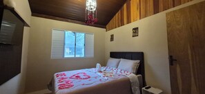 Un dormitorio con cama, ventana, lámpara de techo y puerta.