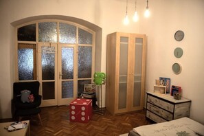 Una habitación con un amplio ventanal arqueado, un armario, un escritorio con silla y una cama.