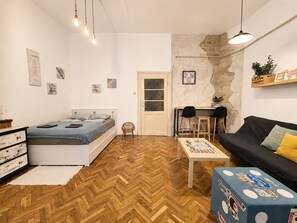 Ein gemütlicher Wohnraum mit Bett, Sofa, kleinem Tisch und Stuhl.