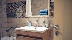 A bathroom with a wooden vanity, a white sink, a handheld showerhead, and patterned tiles on the wall. - Spacious 2bedroom apartment, 4 beds in the DOWNTOWN with FREE PARKING and AC (Budapest)