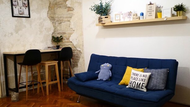 A room with a blue sofa, two chairs, a wooden table, and a stone wall. - Spacious 2bedroom apartment, 4 beds in the DOWNTOWN with FREE PARKING and AC (Budapest)