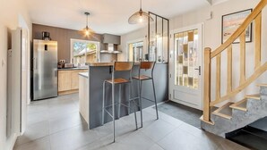 Una cocina moderna con una isla central, electrodomésticos de acero inoxidable y una escalera de madera.