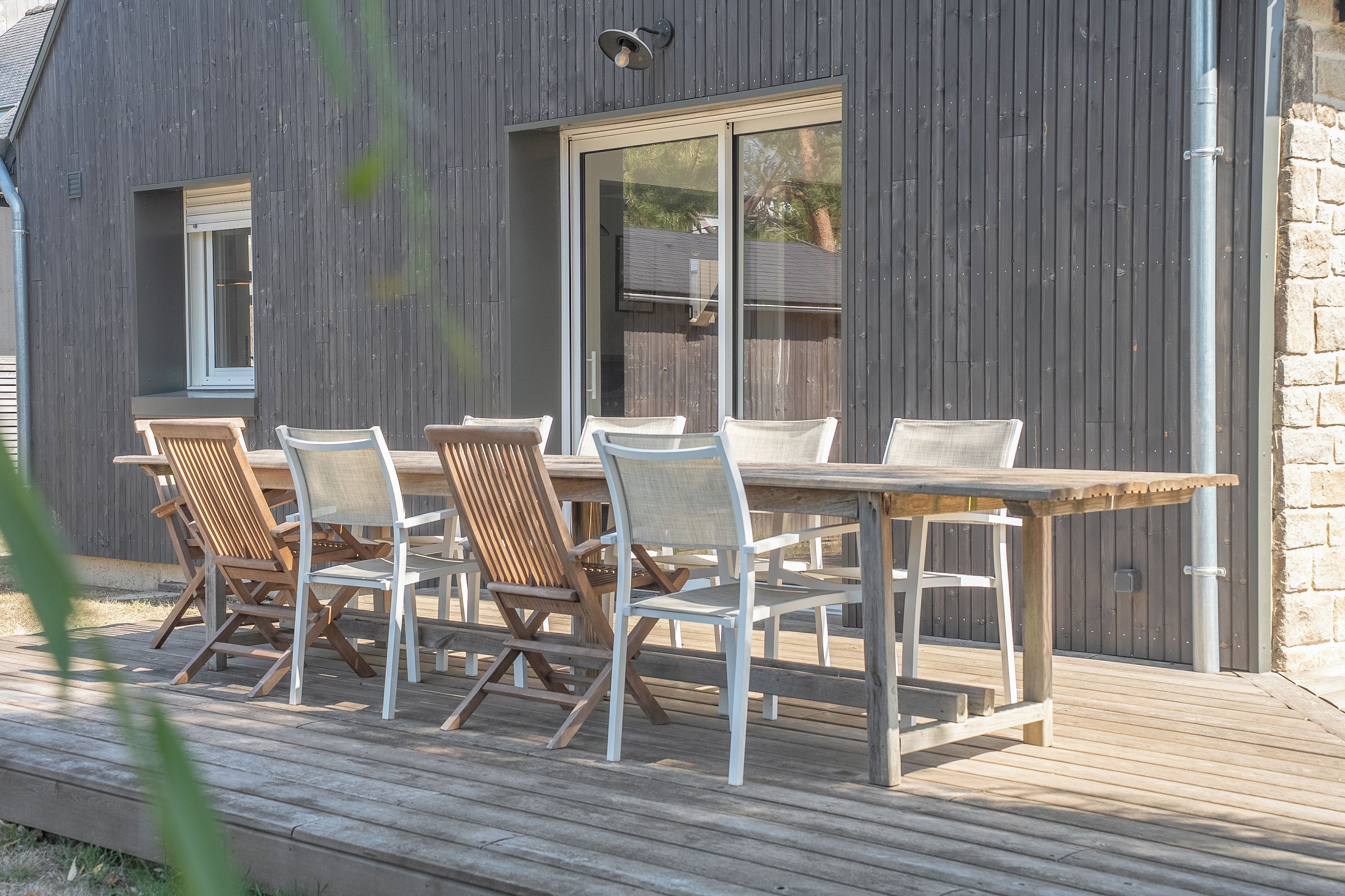 Eine Terrasse mit Tisch, Stühlen, einem Fenster und einer Tür.