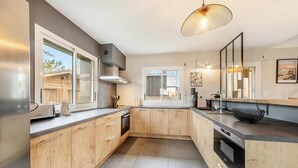 Una cocina moderna con armarios de madera, horno integrado y un amplio ventanal.