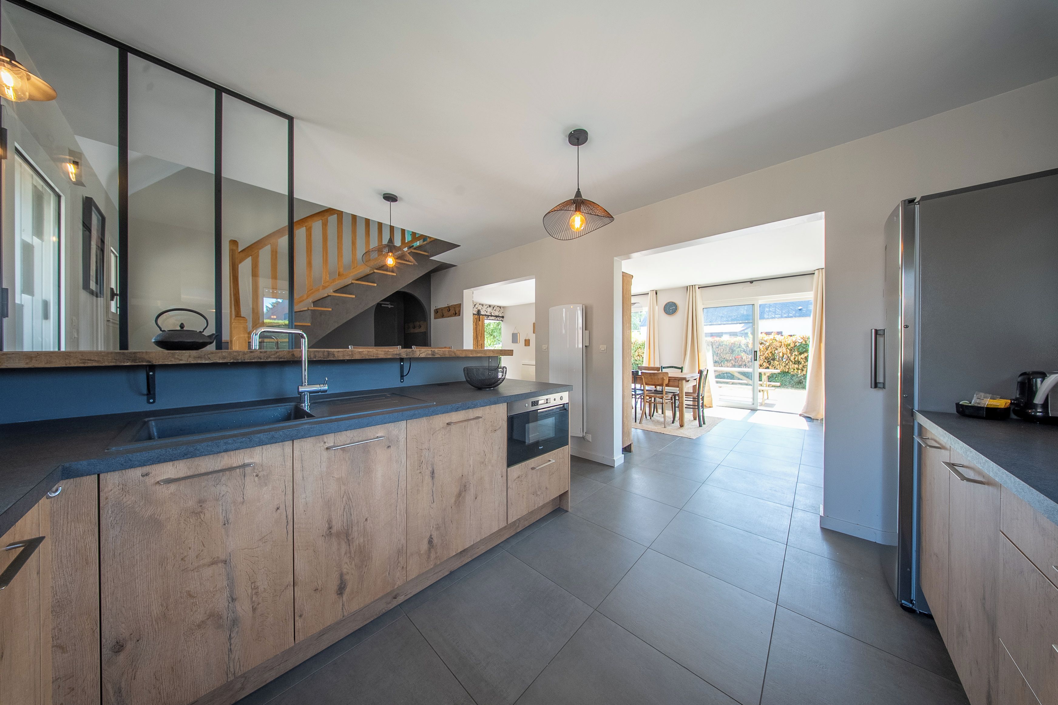 A modern kitchen with wooden cabinets, a built-in oven, and a stainless steel refrigerator.