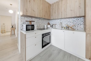 Eine moderne Küche mit weißen Schränken, einer Mikrowelle, einem Toaster und einem Backofen.