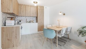 Una cocina moderna con armarios de madera, encimera blanca y una zona de comedor con mesa y sillas.