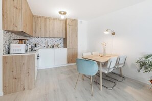 Eine moderne Küche mit Holzschränken, einer weißen Arbeitsplatte und einem Essbereich mit Tisch und Stühlen.