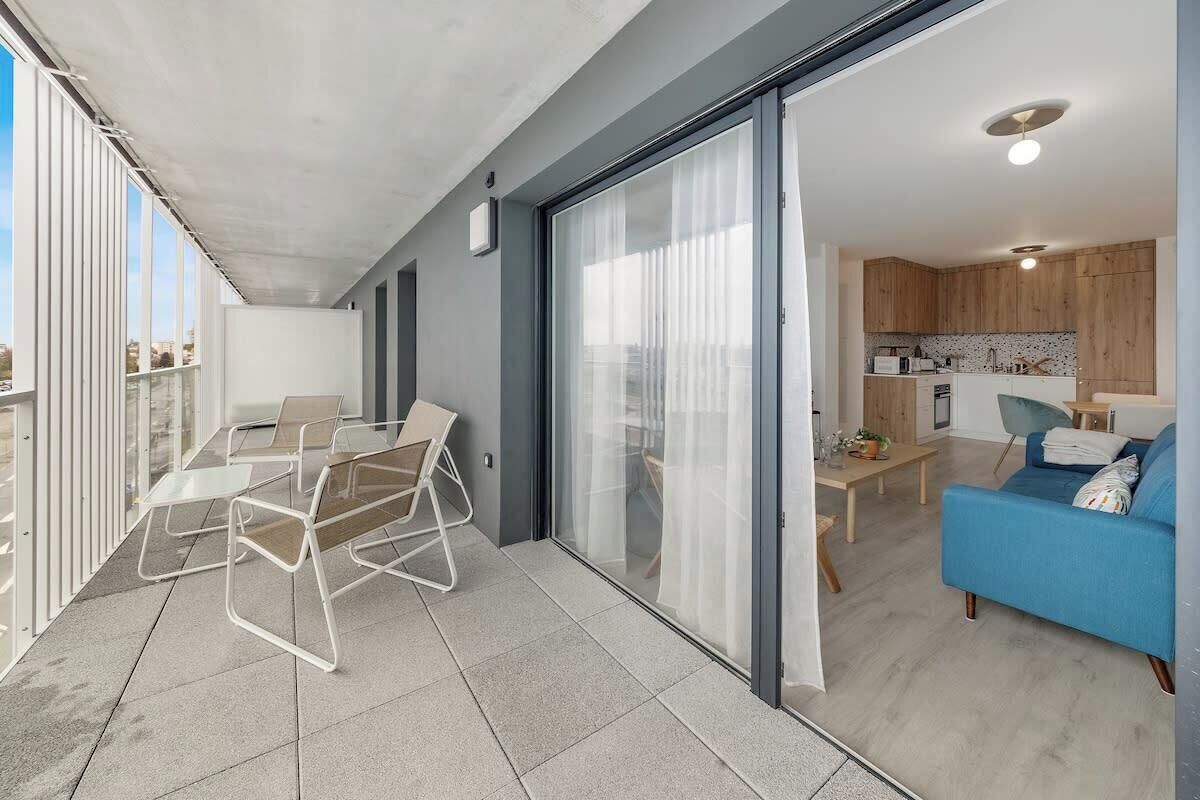 A modern apartment with a balcony, a dining area, and a kitchen.